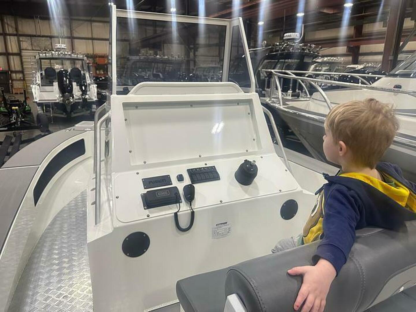 Slide: The Image of Cool Kid on the 2025 Extreme Boats 645 21' Center Console Helm view with Kid Lounging on the 2025 Extreme Boats 645 21' Center Console - 5254790