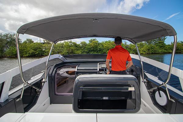 Slide: The Image of 2021 Fairline F Line 33 yacht cockpit with canopy and person at helm. - 11