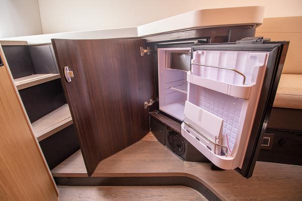 Slide: The Image of Fairline F Line 33 2021 yacht interior with open mini fridge and storage shelves. - 25