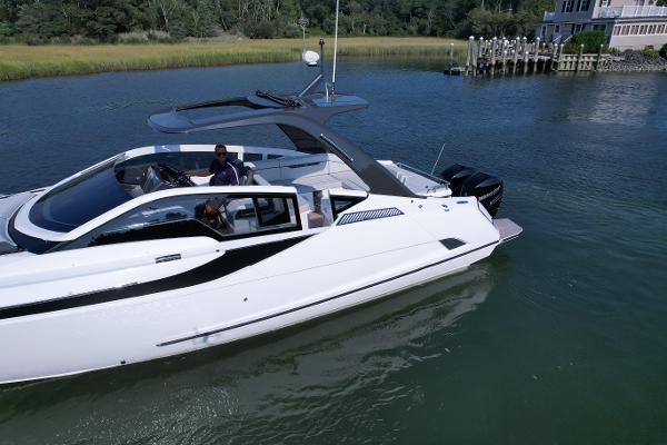 Slide: The Image of 2023 Fairline F//Line 33 Outboard luxury yacht cruising on a serene waterway. - 4