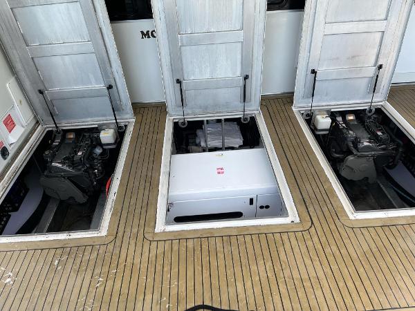 Slide: The Image of 2009 Fantasy Houseboat engine compartments with open hatches on wooden deck. - 36