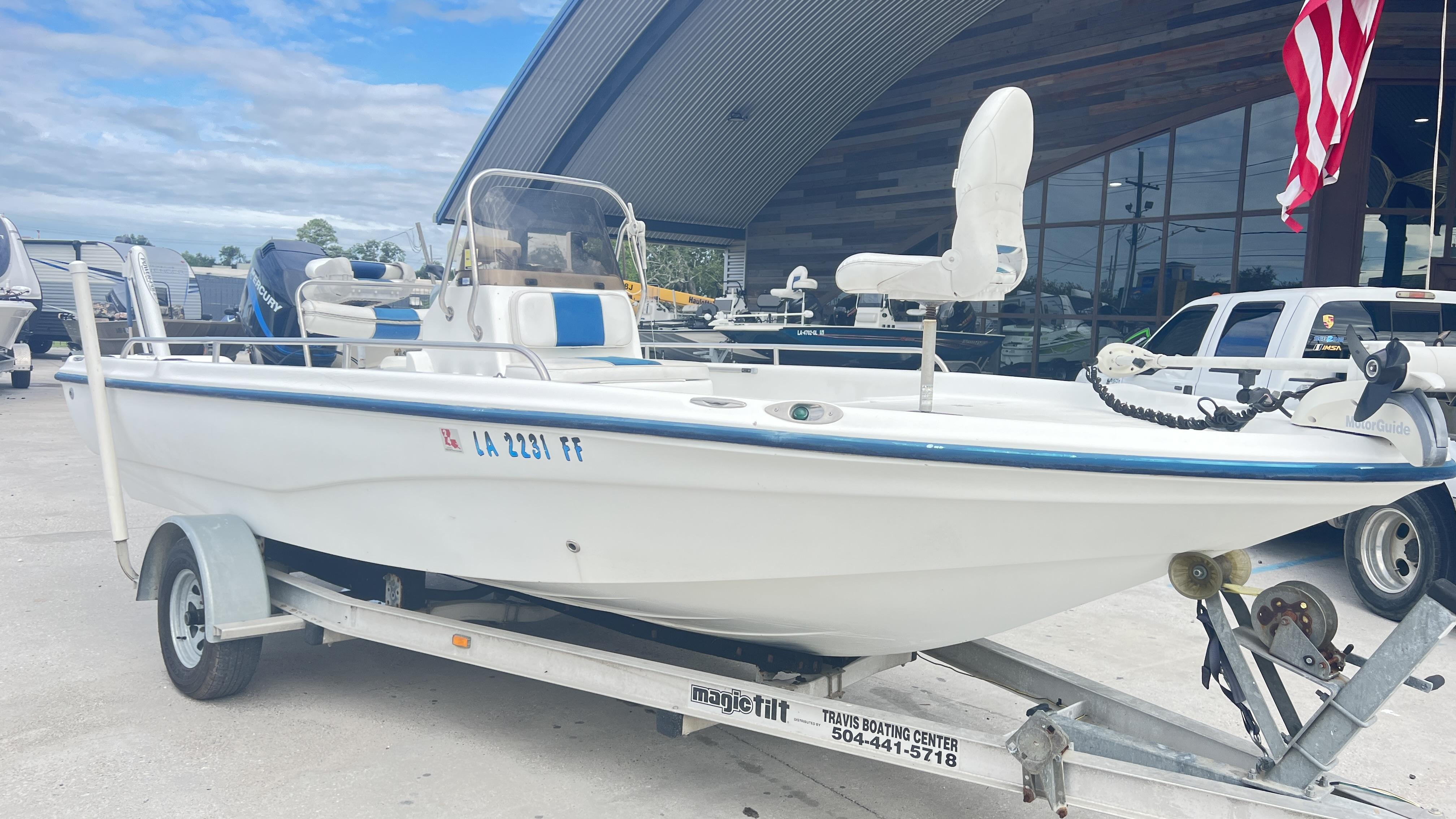 Slide: The Image of 2002 Fishmaster 1900 boat on trailer, parked outdoors near a building. - 2