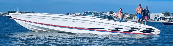 Slide: The Image of 2000 Formula 382 FASTech boat with three people onboard, cruising near the shore. - 21