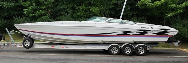 Slide: The Image of 2000 Formula 382 FASTech speedboat on trailer, parked on road with lush green background. - 23