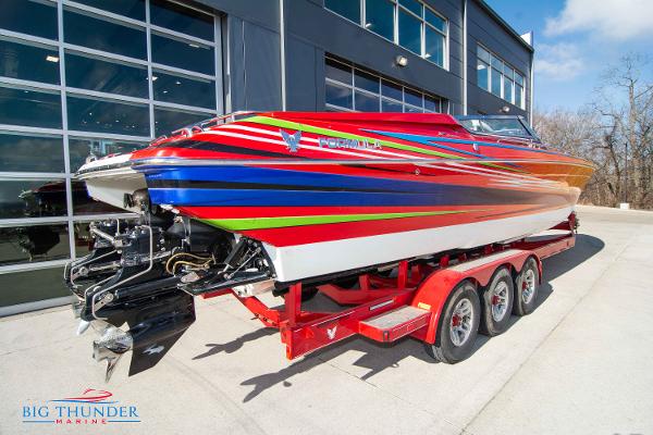 Slide: The Image of 2012 Formula 382 FASTech boat on a red triple-axle trailer outside Big Thunder Marine. - 5