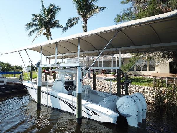 Slide: The Image of 2008 Fountain 34 CC boat docked under canopy with palm trees in background. - 1