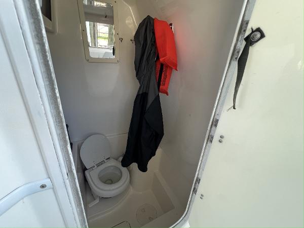Slide: The Image of 2008 Fountain 34 CC boat bathroom with toilet and hanging jackets. - 28