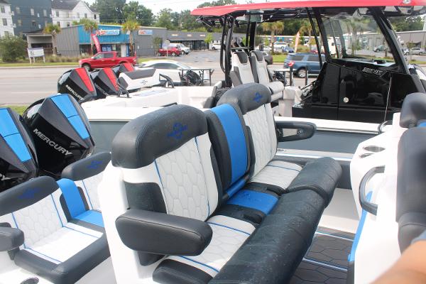 Slide: The Image of 2024 Fountain 34 SC boat interior with blue and white seating, docked in a marina. - 28