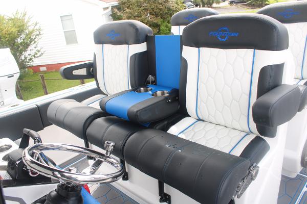 Slide: The Image of 2024 Fountain 34 SC boat interior with black and white seats, blue accents, and steering wheel. - 31