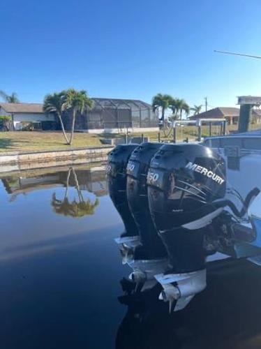 Slide: The Image of 2005 Fountain 38 LX boat with triple Mercury outboard engines docked by a canal. - 4
