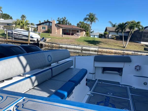Slide: The Image of 2005 Fountain 38 LX boat interior with seating, docked near waterfront homes. - 7
