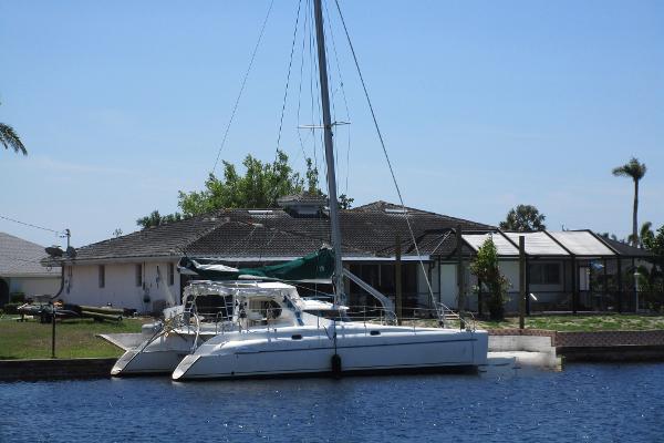 Slide: The Image of 1998 Fountaine Pajot Athena 38 catamaran docked by a waterfront house. - 0