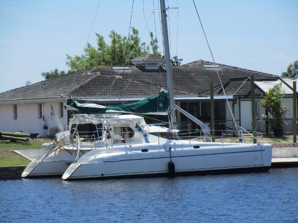 Slide: The Image of 1998 Fountaine Pajot Athena 38 catamaran docked by a waterfront house. - 1