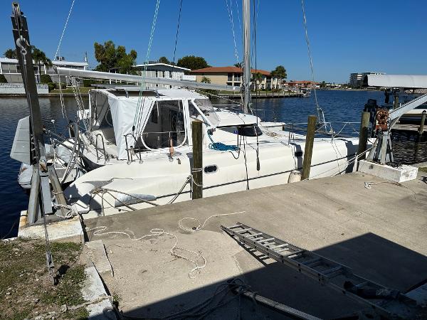 Slide: The Image of 1998 Fountaine Pajot Athena 38 catamaran docked at a marina under clear blue skies. - 38