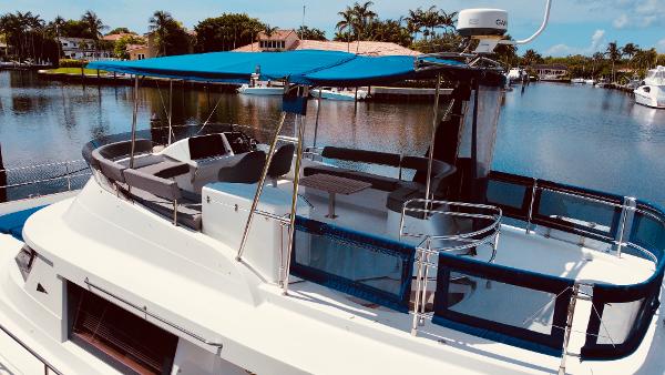 Slide: The Image of 2015 Fountaine Pajot Cumberland 47 LC yacht with blue canopy on a serene waterway. - 13