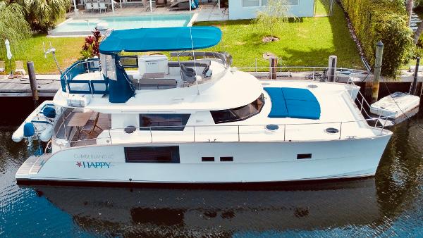 Slide: The Image of 2015 Fountaine Pajot Cumberland 47 LC yacht docked by a waterfront property. - 2
