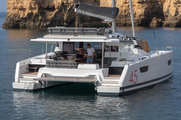 Slide: The Image of 2024 Fountaine Pajot Elba 45 catamaran anchored near rocky cliffs. - 1