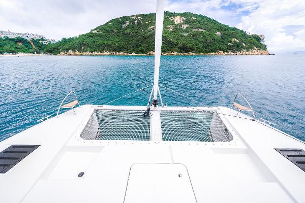 Slide: The Image of 2024 Fountaine Pajot Tanna 47 catamaran sailing near a lush green island. - 1