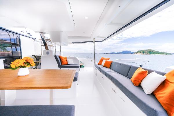 Slide: The Image of 2024 Fountaine Pajot Tanna 47 yacht interior with ocean view, modern seating, and vibrant cushions. - 11