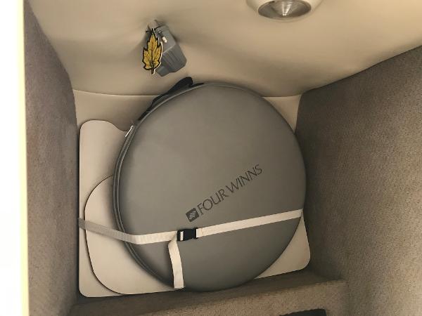 Slide: The Image of Storage compartment in a 2002 Four Winns 245 Sundowner boat with a secured round cushion. - 14