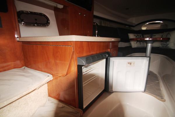 Slide: The Image of 2004 Four Winns 268 Vista cabin interior with open mini fridge and wooden cabinetry. - 29