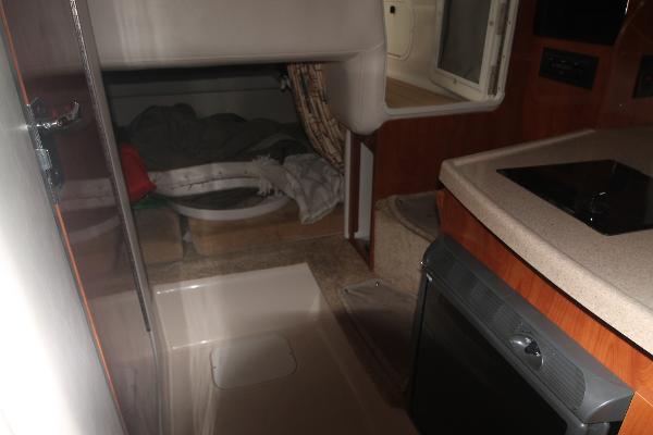 Slide: The Image of Interior of 2004 Four Winns 268 Vista boat, featuring compact kitchen and sleeping area. - 32