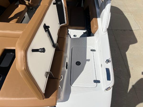 Slide: The Image of 2023 Four Winns H4 boat interior with tan and white seating and storage compartments. - 8