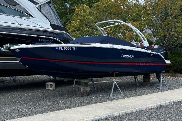 Slide: The Image of 2022 Four Winns H4 OB boat on stands, navy blue with red accents, parked outdoors. - 0