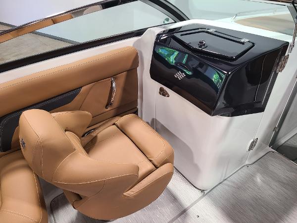 Slide: The Image of 2024 Four Winns HD5 Surf boat interior with tan seating and black console. - 8