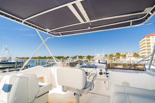 Slide: The Image of 2003 Gibson 47 Classic boat interior with marina view, featuring helm and seating area. - 10