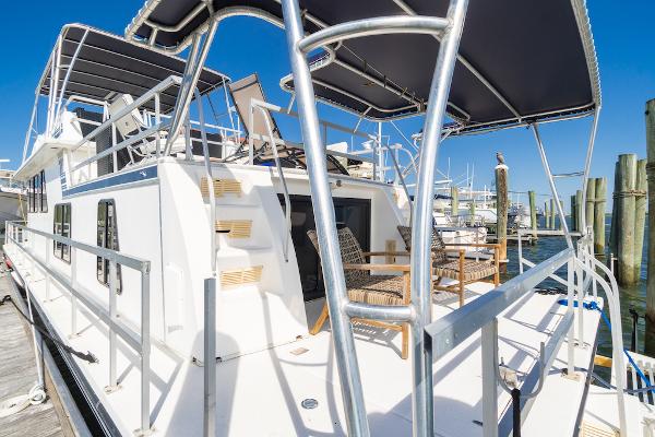 Slide: The Image of Gibson 47 Classic 2003 houseboat docked, featuring spacious deck and seating under canopy. - 13