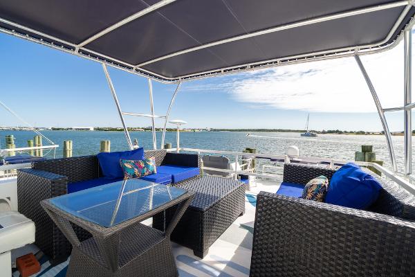 Slide: The Image of 2003 Gibson 47 Classic houseboat with outdoor seating, glass table, and waterfront view. - 16