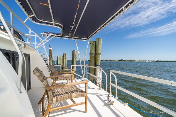 Slide: The Image of Gibson 47 Classic 2003 yacht deck with chairs, overlooking serene water and blue sky. - 3