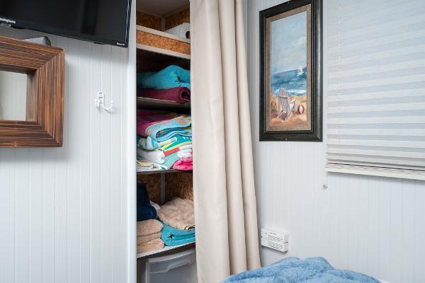 Slide: The Image of Cozy room with a closet of colorful towels, beach painting, and a wall-mounted TV. - 38