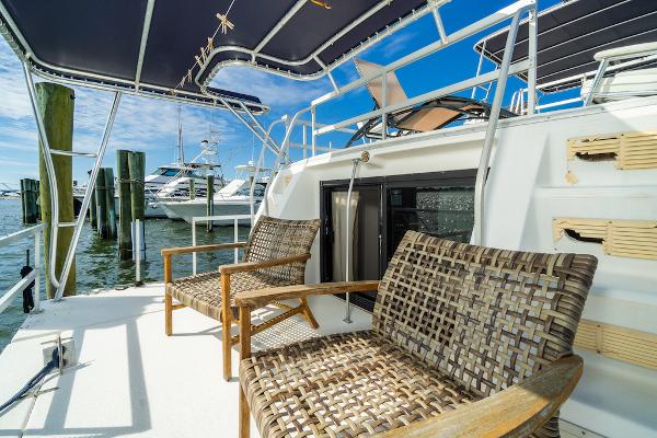 Slide: The Image of 2003 Gibson 47 Classic yacht deck with wicker chairs and marina view. - 6