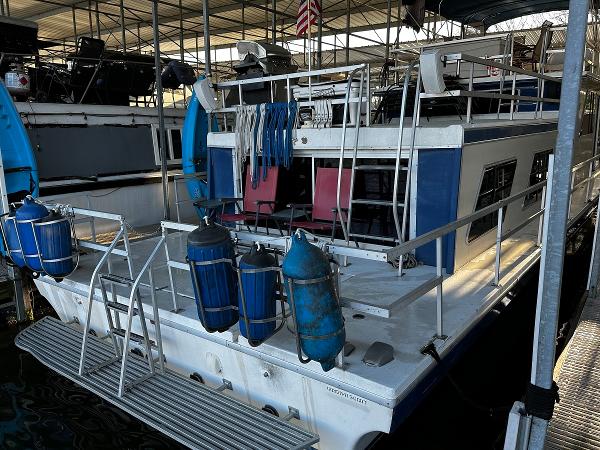 Slide: The Image of 1987 Gibson 50 Classic houseboat docked, featuring upper deck and safety equipment. - 12