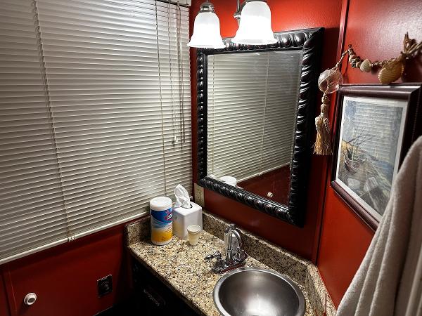 Slide: The Image of Small bathroom with red walls, granite countertop, and framed mirror above sink. - 26