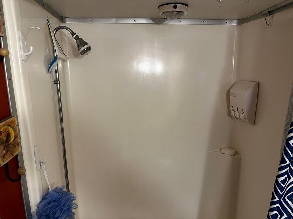 Slide: The Image of Compact shower stall with showerhead, soap dispenser, and blue loofah. - 28