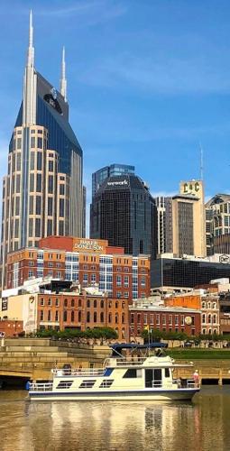 Slide: The Image of Gibson 50 Classic 1987 boat on river with city skyline background. - 40
