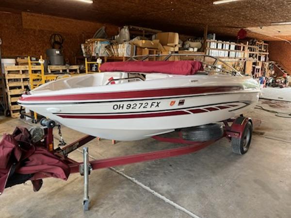 Slide: The Image of 2007 Glastron GT185 boat on trailer in a garage, red and white design. - 0