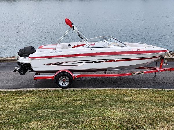 Slide: The Image of 2008 Glastron GT 205 boat on a red trailer by the water. - 0