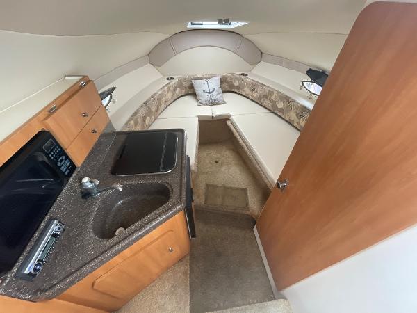 Slide: The Image of 2009 Glastron GT 249 cabin interior with kitchenette and seating area. - 11