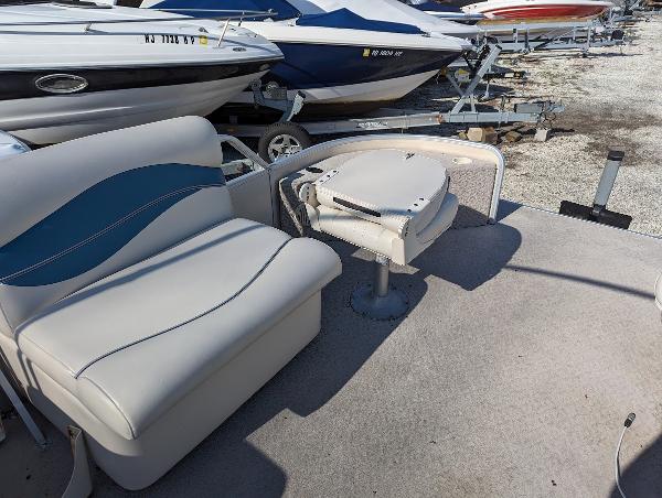 Slide: The Image of 2006 Godfrey Sweetwater boat interior with seating and table, parked among other boats. - 18