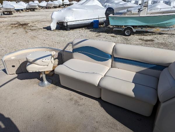 Slide: The Image of 2006 Godfrey Sweetwater boat interior with beige and blue seating, parked outdoors. - 19