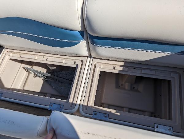 Slide: The Image of Open storage compartments on a 2006 Godfrey Sweetwater boat with blue and white seating. - 20