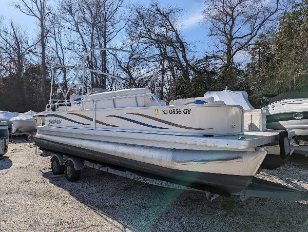 Slide: The Image of 2006 Godfrey Sweetwater pontoon boat on trailer, parked outdoors, with trees in the background. - 4