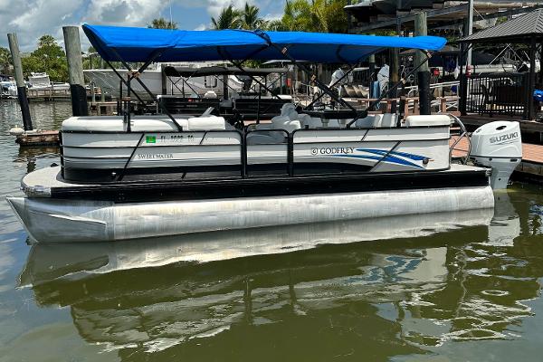 Slide: The Image of 2022 Godfrey Sw Mid Table Tri-Toon pontoon boat docked with blue canopy. - 0