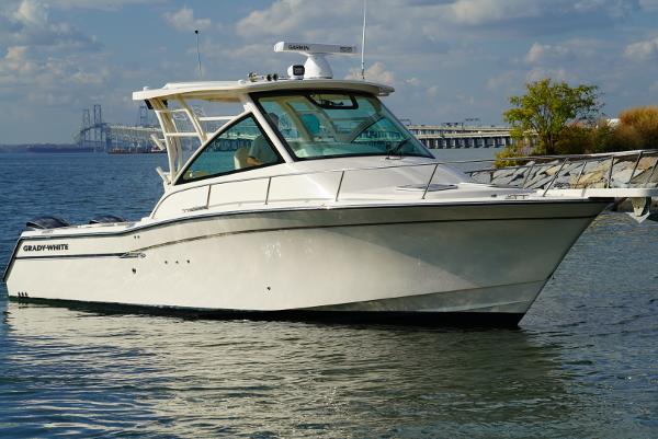 Slide: The Image of 2016 Grady-White Express 330 boat on calm water near a bridge and shoreline. - 0