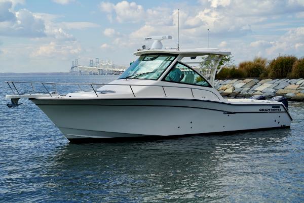 Slide: The Image of 2016 Grady-White Express 330 boat on calm water near rocky shoreline. - 7