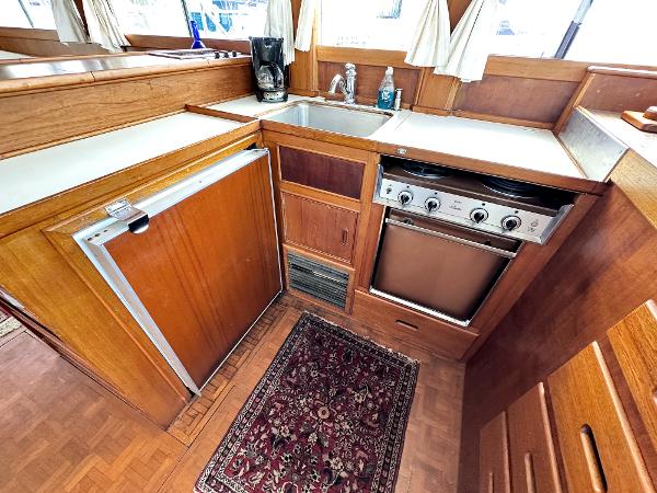 Slide: The Image of 1980 Grand Banks 42 Europa yacht kitchen with wood cabinetry, stove, sink, and fridge. - 40